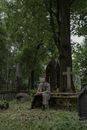 A Man Smoking a Cigarette while Sitting on a Grave