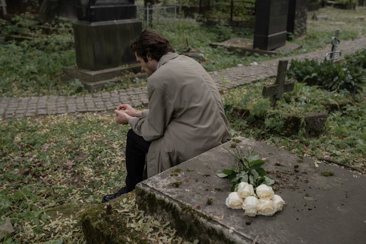 A Man Sitting By A Grave