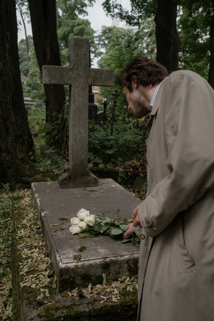 A Man Placing Flowers On A Grave