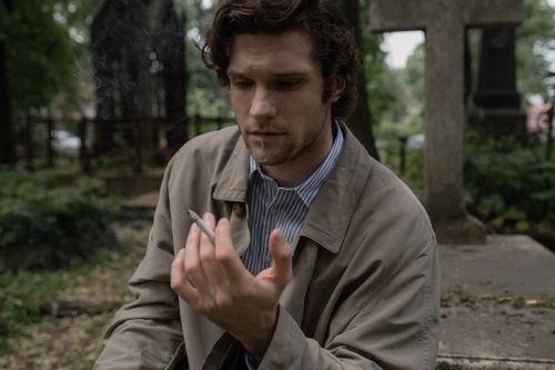 Free A thoughtful man in a trench coat smokes in a cemetery, evoking themes of grief and reflection. Stock Photo