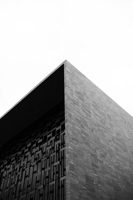 Low-angle shot of modern building architecture in black and white, emphasizing geometric lines.