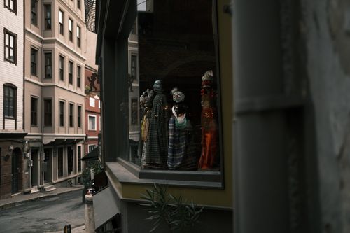 Free A street scene showcasing a window display with puppets in an urban setting. Reflective and moody atmosphere. Stock Photo