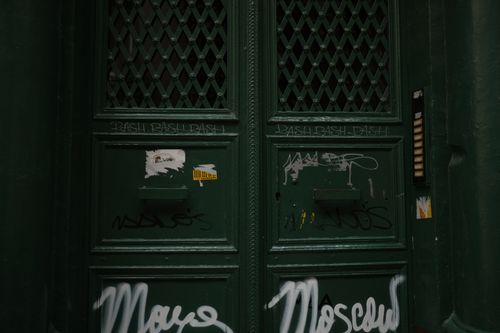 Free Close-up view of a dark green door covered with graffiti and tags, showcasing urban street art. Stock Photo