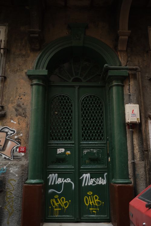 Free Decorative green door with graffiti adds urban character to an old building. Stock Photo