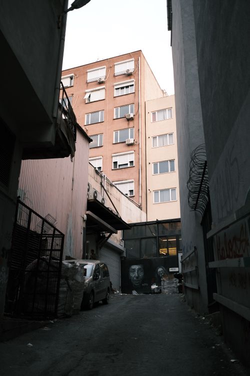 Free Narrow urban alley with towering buildings and street art, offering a raw cityscape view. Stock Photo