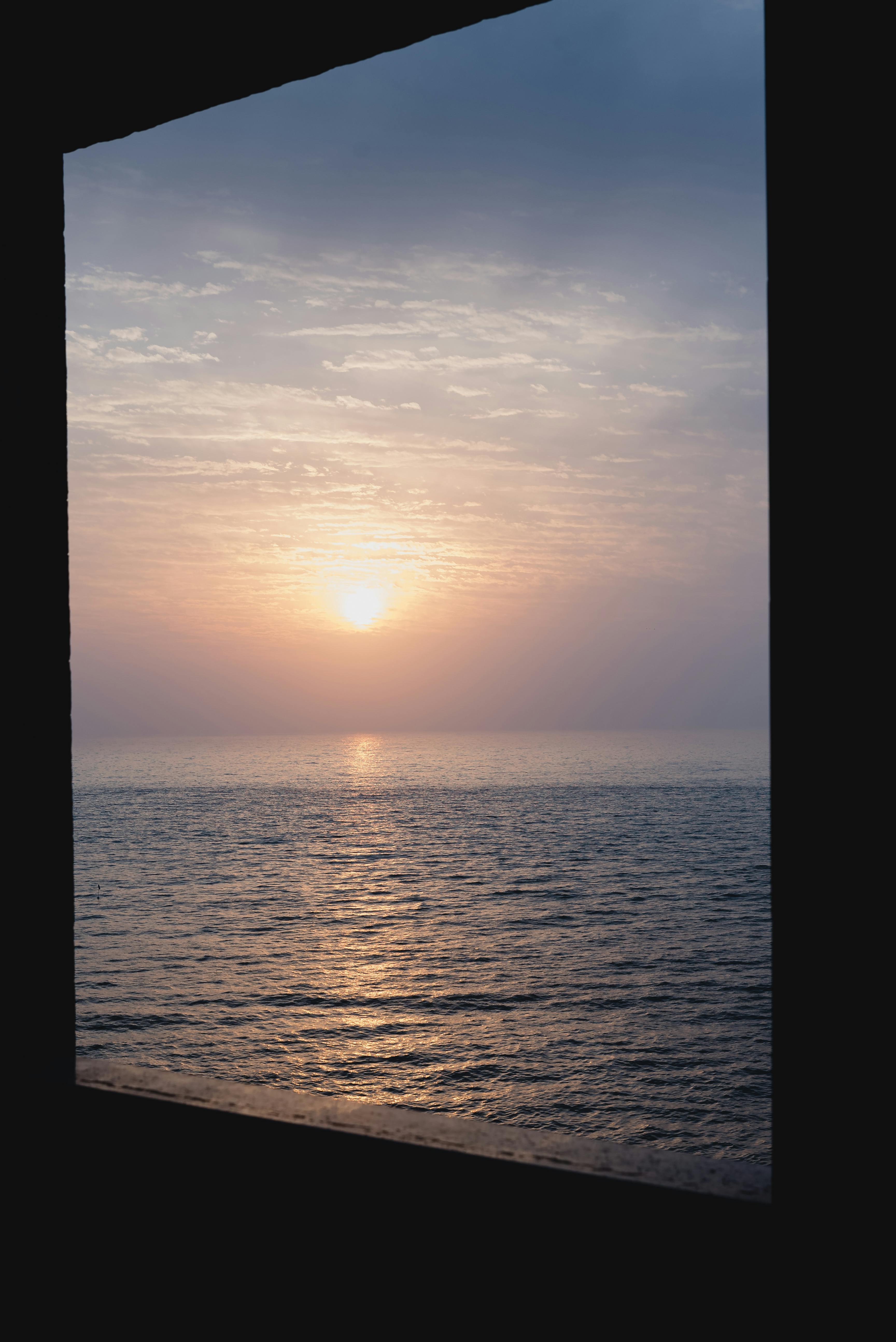 Free Stunning sunset over the ocean as seen from Rio de Janeiro, framed by a window. Stock Photo