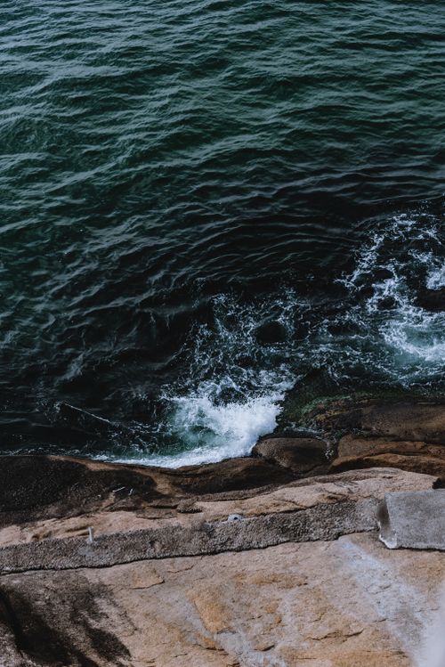 Free High angle view of ocean waves crashing onto rugged rocky shore, capturing nature's raw power. Stock Photo