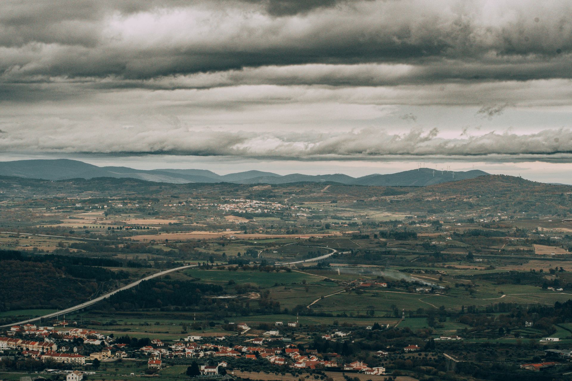 Dramatic aerial view of Covilhã's lush landscape with cloudy skies and rolling hills in Portugal.