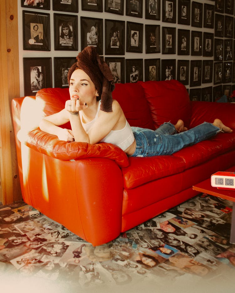 Woman With Towel On Head Lying On Red Sofa 