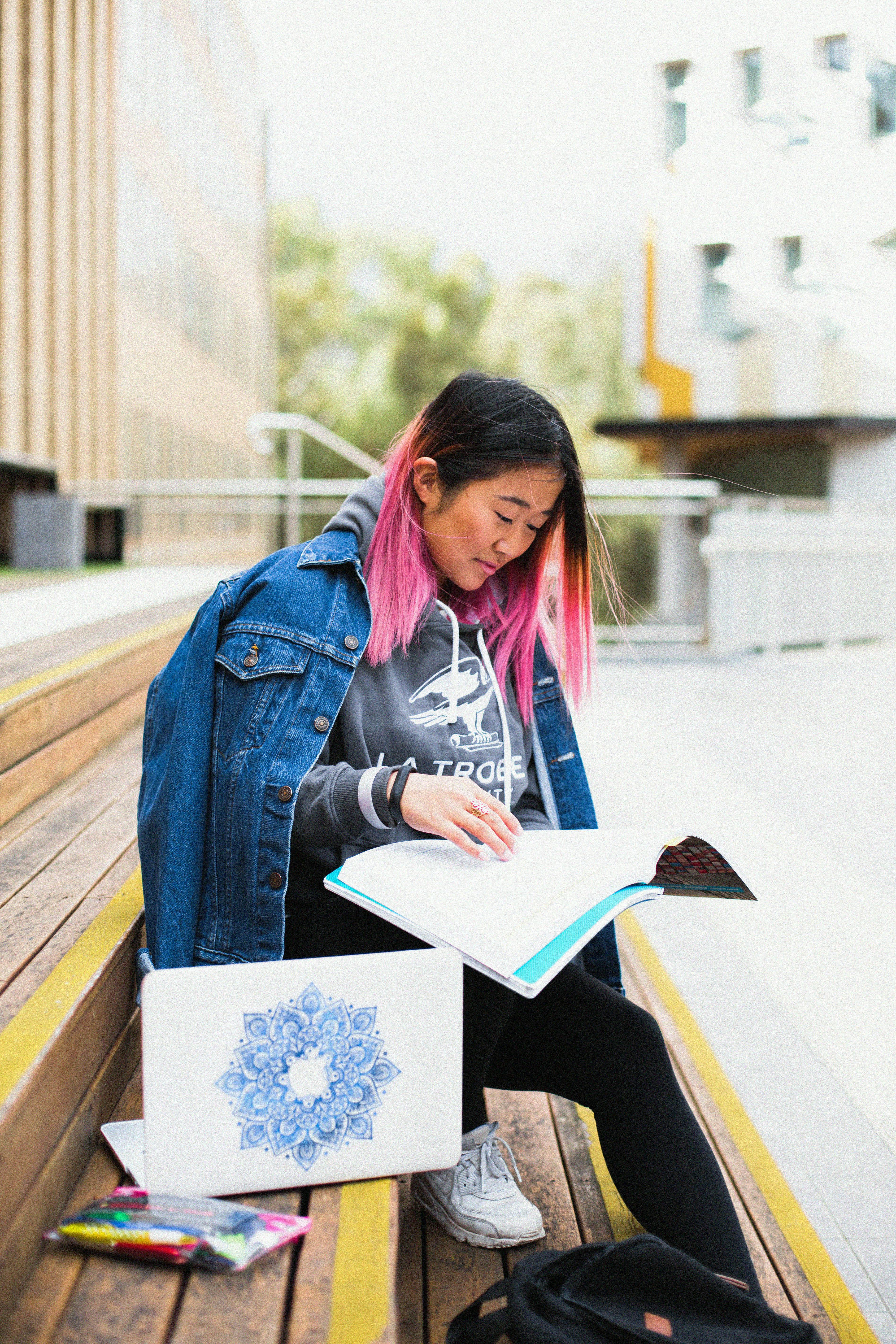 woman in blue denim jacket holding books