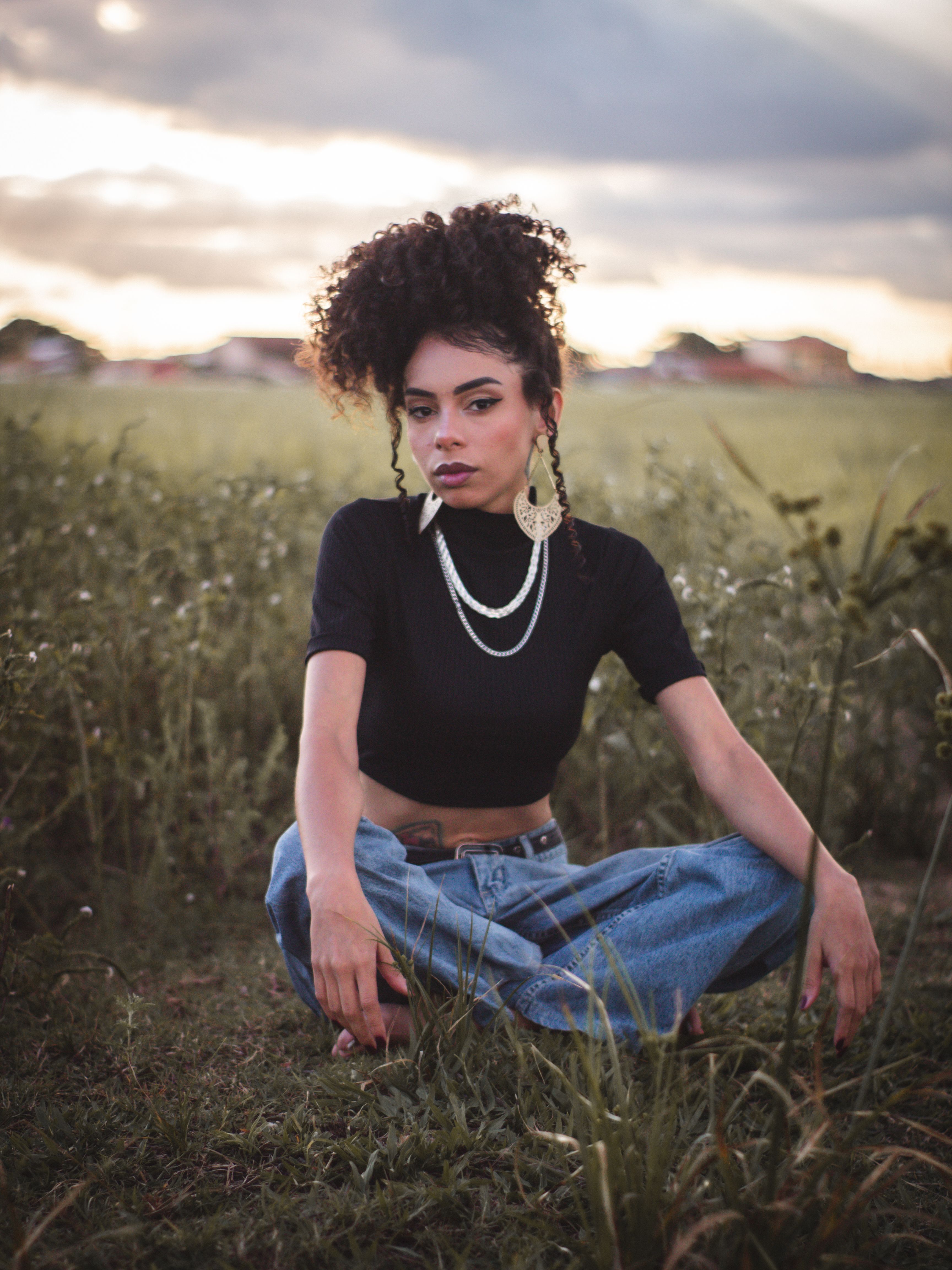 Woman in White Top and Denim Jeans Sitting on a Barrier · Free Stock Photo
