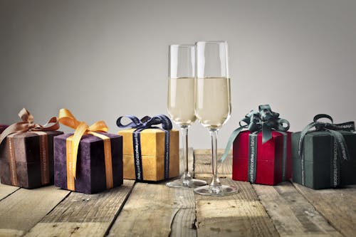 Five Assorted-color Gift Boxes and Two Footed Glasses on Top of Table