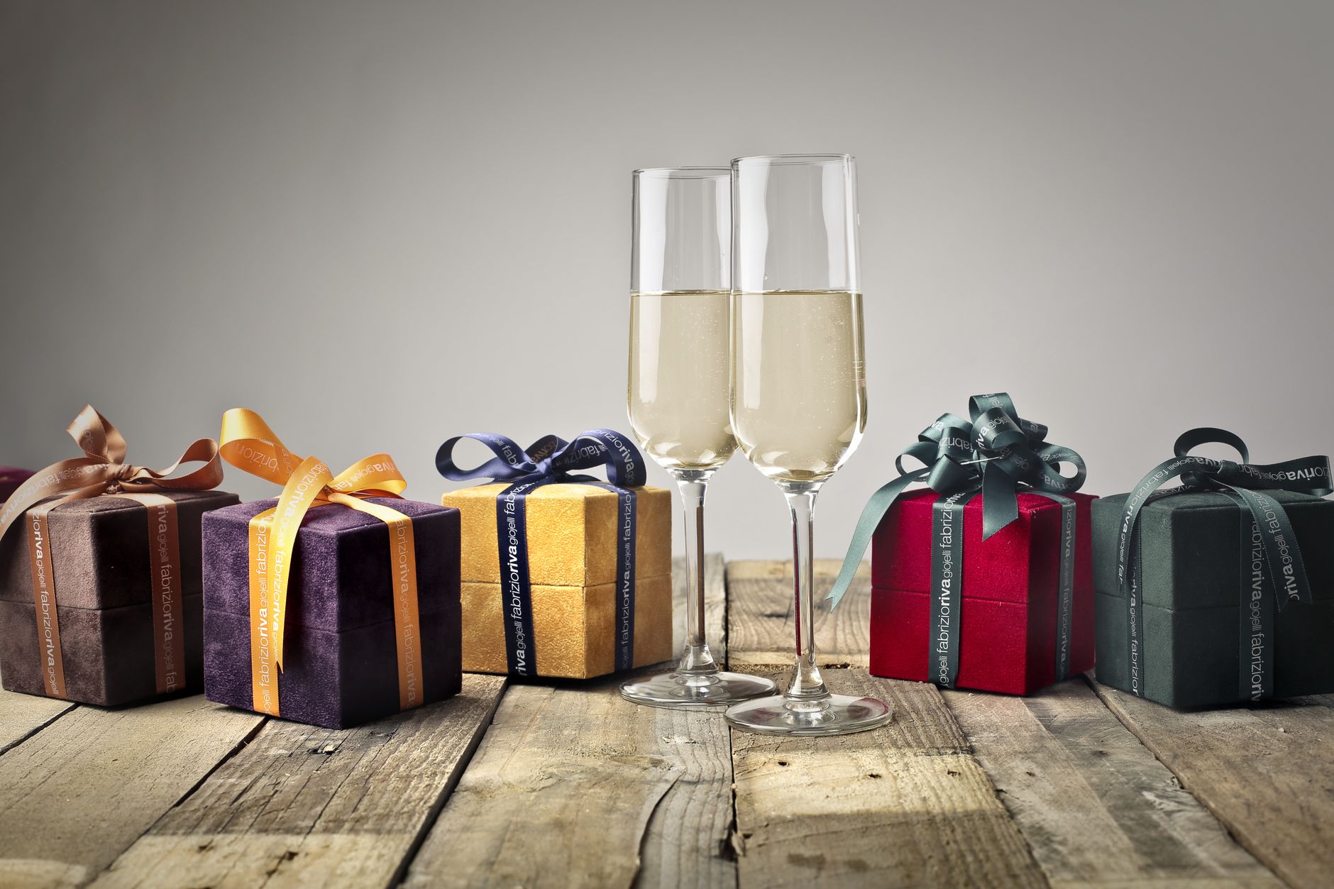 Luxurious gifts with ribbons and champagne flutes on a wooden table, perfect for celebrations.