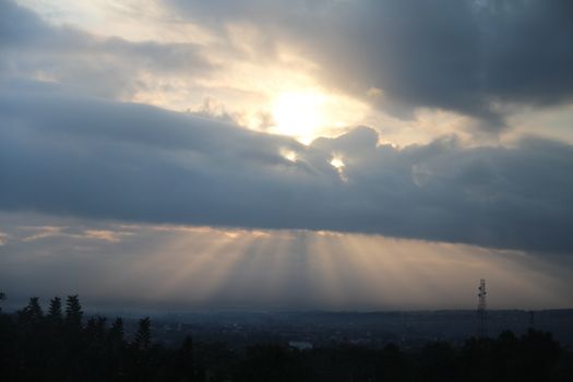 Sunrays breaking through clouds at sunrise over West Java landscape.