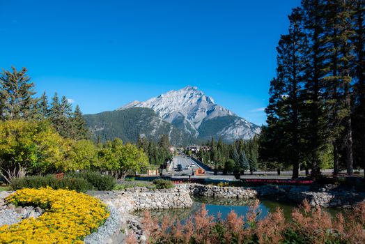Explore the stunning Mount Rundle with lush gardens and clear blue skies in Banff National Park.