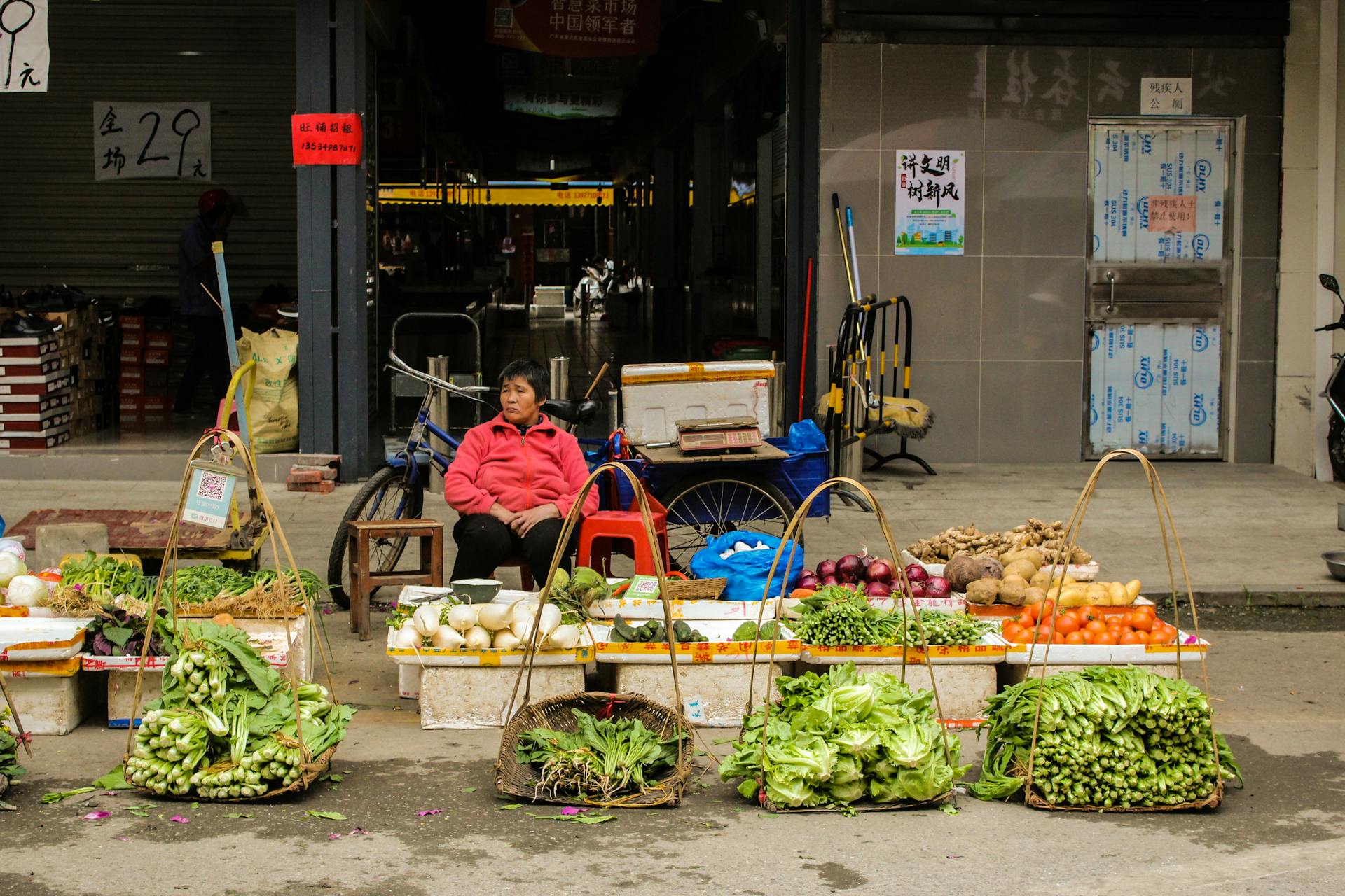 A street vendor in China selling fresh vegetables at a local market. Daily life depicted.