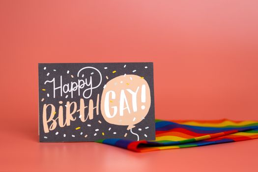 A vibrant 'Happy Birthgay' greeting card displayed with a rainbow flag on a warm backdrop.