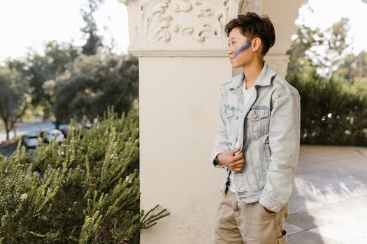 Woman with rainbow makeup standing by ornate column outdoors.