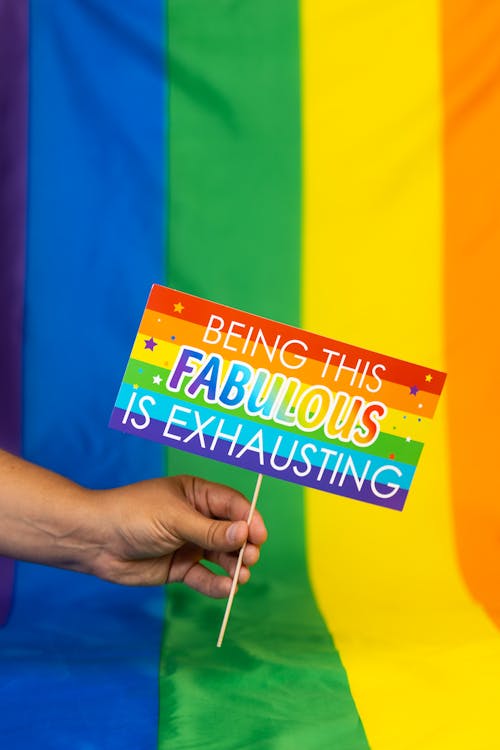 Free Hand Holding Sign in Front of Rainbow Flag Stock Photo