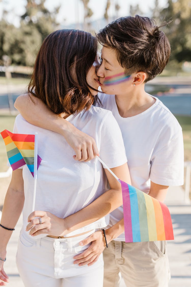 Lesbian Couple Kissing And Holding LGBT Flags