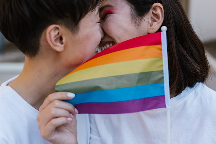 Two Women Leaning In For Kiss Holding Rainbow Flag