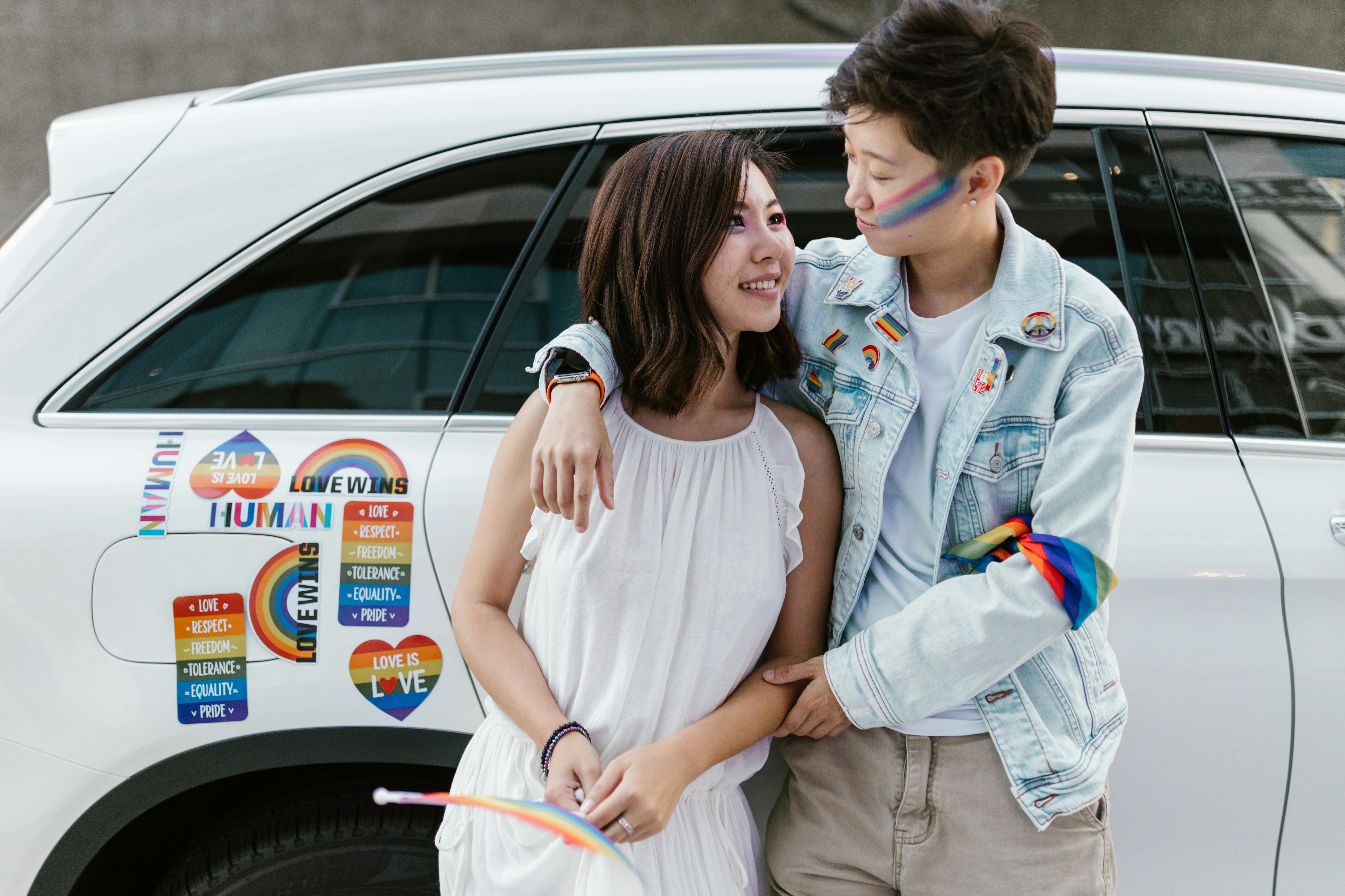 lesbian couple embracing leaning on car