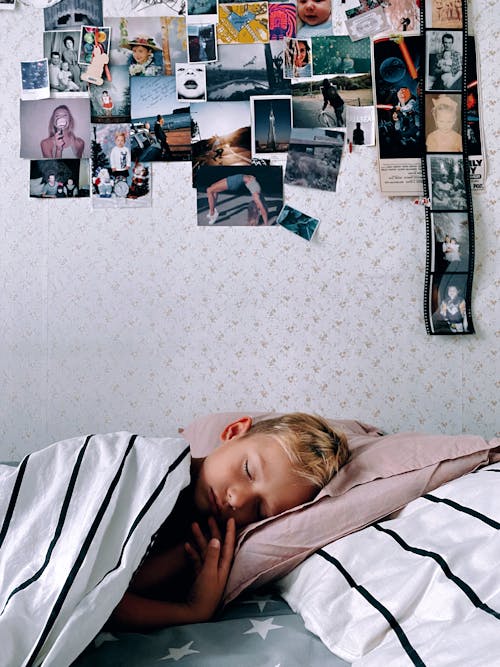 Free Boy Sleeping on Bed Beside the Wall with Picture Stock Photo
