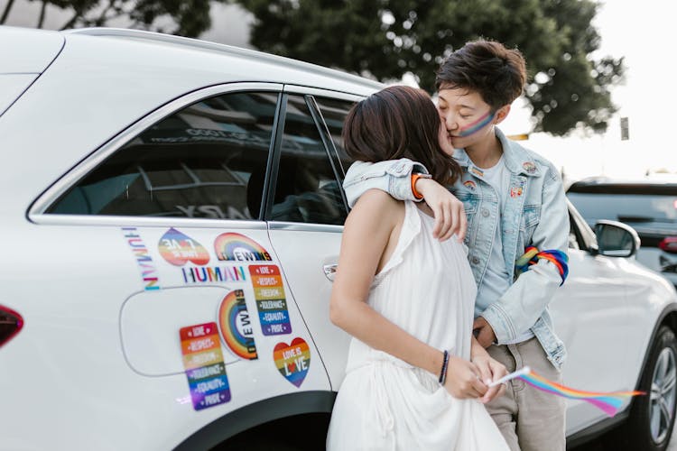 Two Lesbian Women Kissing Each Other Standing At Car With Rainbow Labels 