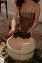 Woman Putting a Bunch of Grapes into the Wooden Vat