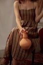 Woman Sitting on a Chair and Holding an Earthen Ewer