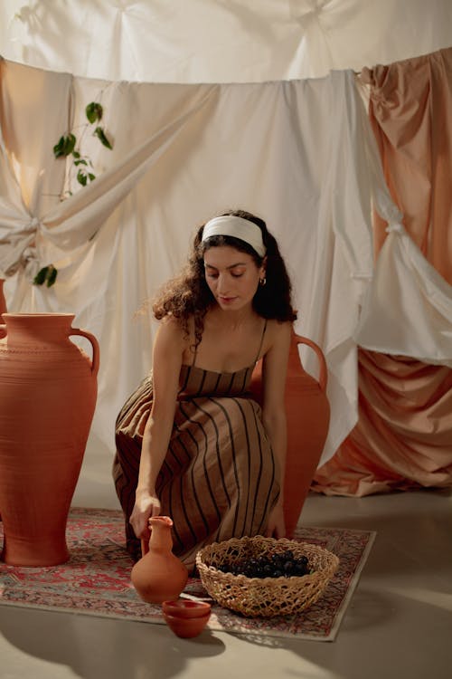 Crouching Woman in Dress Holding Ceramic Jug