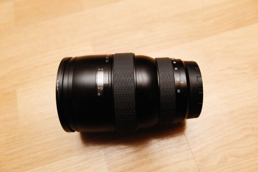 Close-up of a DSLR camera lens on a wooden surface, ideal for photography enthusiasts and professionals.