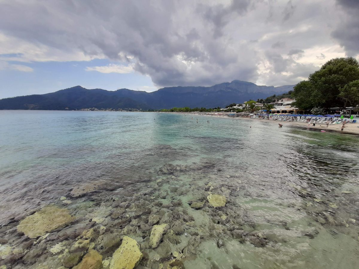 Plaja cu apa cristalina si munti verzi in fundal, in Thassos