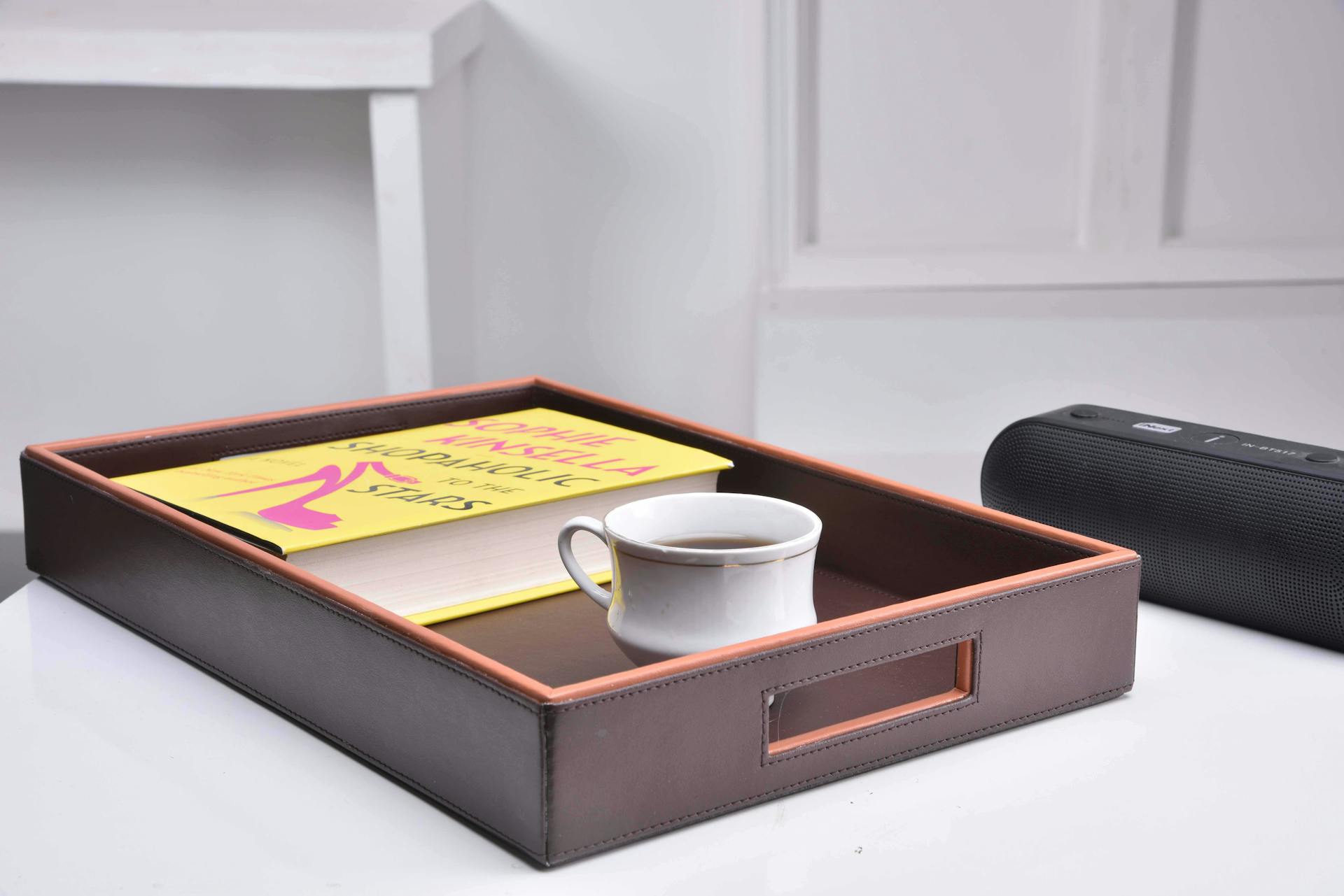 A modern home decor setup featuring a leather tray with a book and coffee cup, indoors.