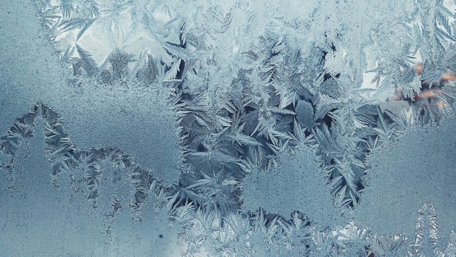 Close-up of intricate frost patterns on a cold winter glass panel.