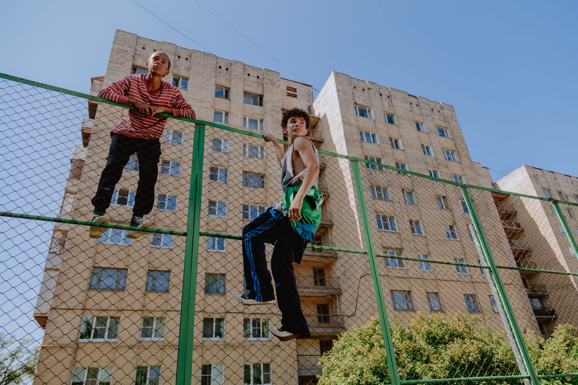 Boys Climbing the Metal Fence