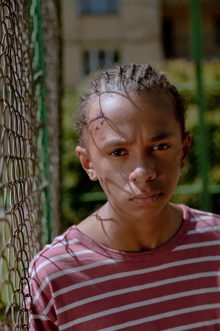 Boy Standing By Netting Fence