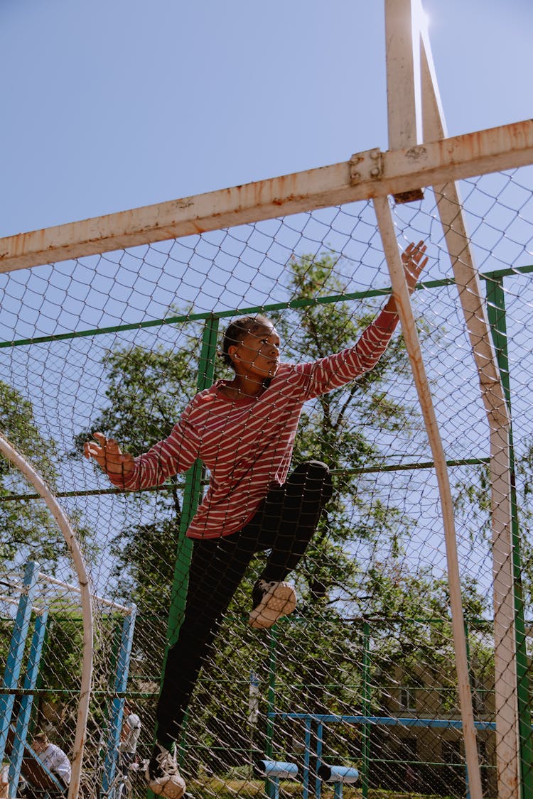 A Kid Climbing A Wire Fence