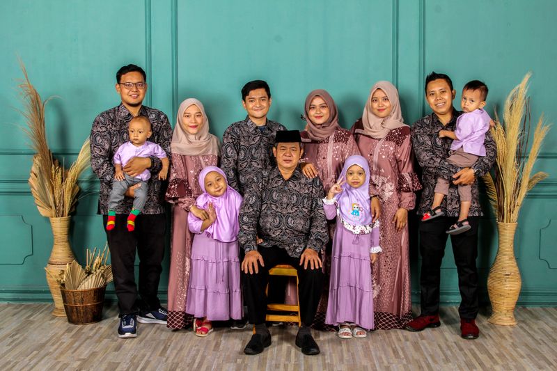 A large family group posing in matching traditional outfits, smiling indoors.