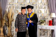 Woman in Black Academic Dress Standing Beside White Wooden Shelf