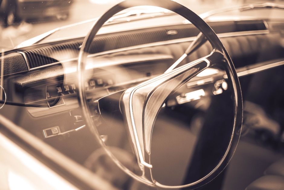 Close-up of a vintage car steering wheel in sepia, highlighting classic design details.