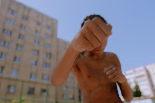 Teenager throwing a punch outside with urban buildings in the background.
