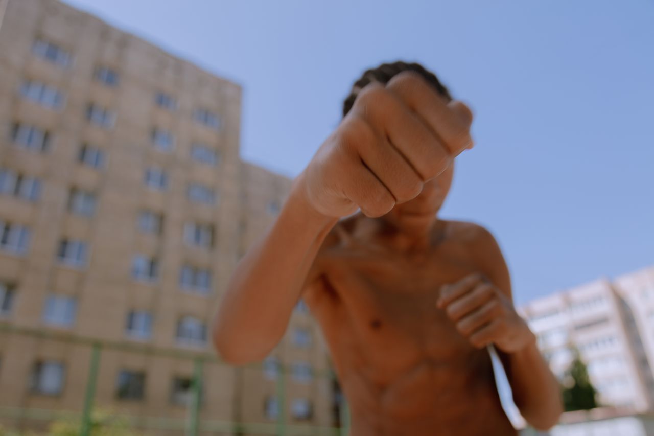 teenager throwing a punch outside with urban buildings in the backgrou