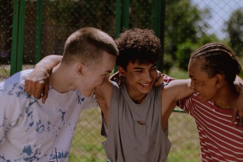 Diverse group of teenage friends laughing and embracing outdoors
