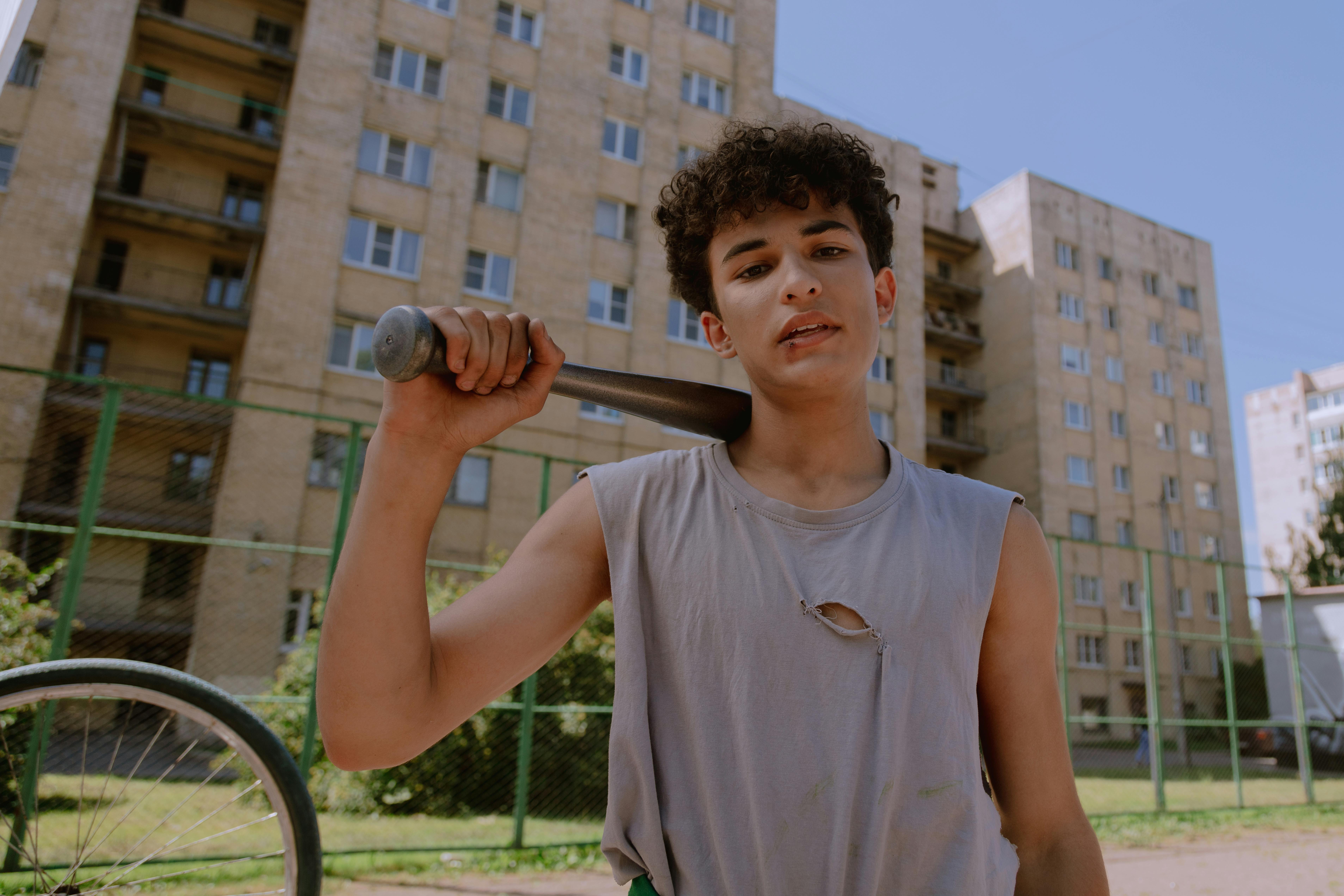 teenage boy in gray tank top holding a baseball bat