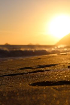 Captivating view of a beach at sunset with glowing sun and gentle waves.