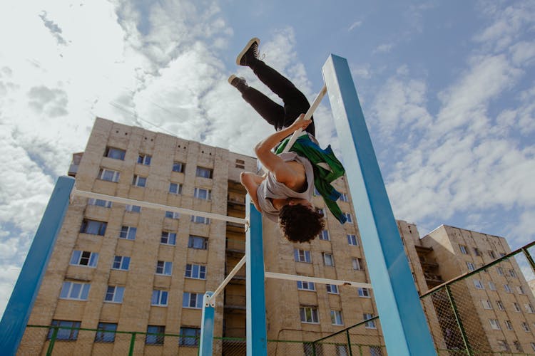 A Boy Hanging On A Pull Up Bar