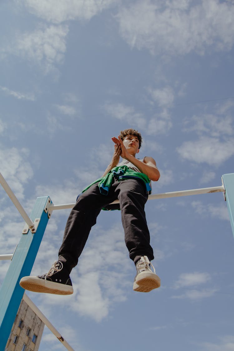 A Boy Sitting On A Monkey Bar