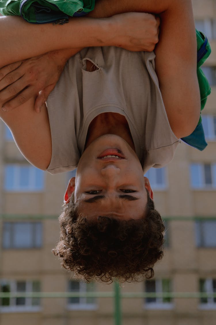 Boy In Sleeveless Shirt Hanging Upside Down