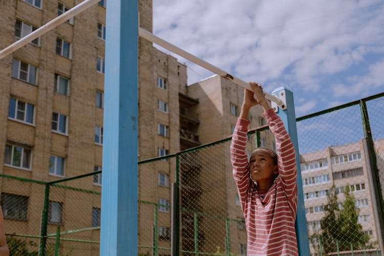 A Boy Holding On To A Bar